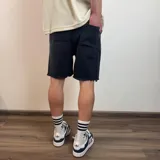 Bermuda de jean color negro con efecto desgastado y roturas, corte jogger arriba de la rodilla y cintura con cordón ajustable.