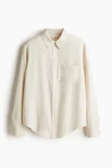 Camisa color crema de mezcla de lino y viscosa con cuello, botones adelante y canesú de doble capa con pliegue de caja en la espalda. Modelo de manga larga con bolsillo superior abierto, puños abotonados y bajo redondeado.