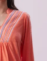 Blusa blanca de poliéster y rayón con escote en V bordado y mangas tres cuartos regulables con presilla y botón.