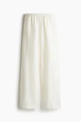 Pantalón blanco de lino con cintura elástica, bolsillos al bies y bolsillos traseros insertados. Piernas rectas con pliegue cosido adelante.