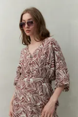Vestido corto color marrón con estampado de hojas blancas, escote en V, mangas cortas y cintura marcada.