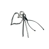 Llavero con dije metálico plateado en forma de corazón y cordón negro. Incluye dos cadenas metálicas plateadas de diferente grosor.