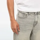 Pantalón de jean gris, corte ancho y tiro medio, con cinco bolsillos.