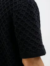 Polo negro de tejido cable knit con fit relajado, cuello tipo polo, manga corta y cierre con botones.