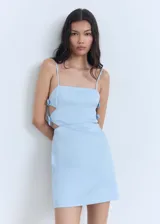 Vestido corto celeste con breteles finos, escote recto, corte ajustado, aberturas laterales y lazos decorativos en los laterales. Cierre con cremallera en la parte posterior.