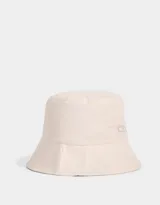 Piluso color beige de tela deportiva, reversible, con etiqueta de goma con logo de la marca.