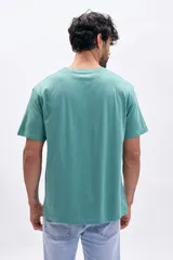 Remera verde de manga corta con estampa frontal con la frase "Urban Trek city pulse street vibe subway beat".