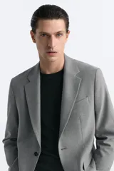 Blazer straight fit color gris claro confeccionado en tejido con viscosa. Tiene cuello con solapas de muesca, manga larga acabada en puño con botón, bolsillo de vivo en pecho, bolsillos de plastrón en cadera y bajo con aberturas en espalda. Cierre frontal de botonadura.