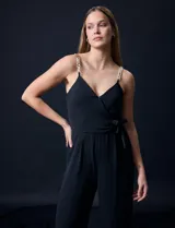 Enterito celeste de crepe marca Luxology, con escote en V cruzado, cintura elastizada, espalda en punto smock y tirantes con detalle de cadenas.