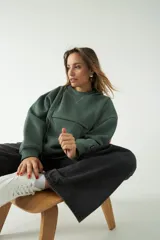 Buzo canguro verde con corte recto y amplio, capucha con cordones regulables y bolsillo frontal con cierre.