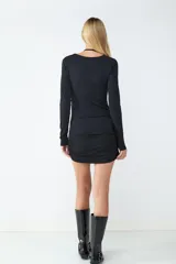 Vestido mini negro de manga larga en tejido elástico, con diseño ceñido al cuerpo y detalles cut-out en la parte superior. Lazada al cuello.