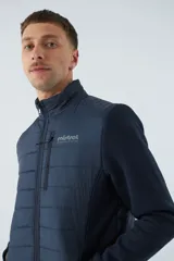 Campera negra con cuerpo acolchado de nylon y mangas de felpa. Tiene cuello alto, cierre frontal, bolsillos laterales con cierre, logo estampado en el pecho y logo de goma en la manga.