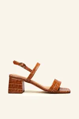 Sandalias de cuero vacuno color marrón con textura tipo reptil, doble tira sobre el empeine, hebilla lateral y taco cuadrado bajo.