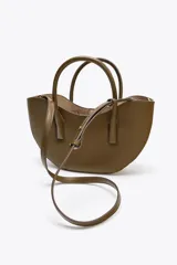Bolso shopper de mano color marrón, con asa doble y correa bandolera extraíble. Tiene cierre imantado y un bolsillo interior con cremallera.