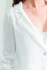 Blazer de lino blanco con estampado floral en tonos rosa y verde, corte holgado, cuello solapa y bolsillos laterales.