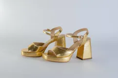 Sandalias de cuero dorado con plataforma y tacón cuadrado. Tira delantera ancha y pulsera con hebilla al tobillo.