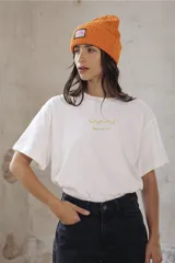 Remera blanca de algodón con estampa rectangular en tonos beige y texto negro.