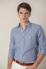 Camisa de manga larga, color azul, confeccionada en lino, con cuello tipo short collar y un pequeño pájaro bordado en amarillo en el pecho.
