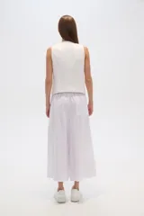 Pantalón blanco de lino, corte ancho, tiro alto y bolsillos laterales.