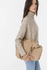 Bolso de cuero color tostado con diseño moderno y cierre ajustable.