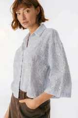 Camisa celeste a rayas verticales blancas con bordado de flores blancas, de corte recto y mangas 3/4.