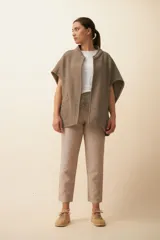 Chaleco color crema de lana sin teñir, corte recto, con cuello y solapa pronunciadas, broches a presión y bolsillos ojal.