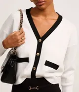 Cardigan negro de punto con escote en V, botones metalizados dorados, bolsillos delanteros falsos, cuello y borde contrastantes en blanco.