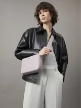 Cartera bandolera Calvin Klein Must, color lila, con correa ancha de tela con el logo de la marca.