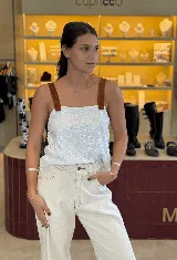 Top blanco con lentejuelas y tirantes finos de cuero marrón.