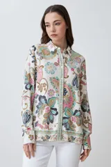 Camisa de manga larga con estampado de arabescos en tonos rosa, celeste, marrón y verde agua sobre fondo blanco. Tiene cuello clásico y cierre con botones.