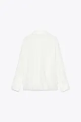 Camisa blanca de manga larga con cuello solapa y bordado de flor en el frente.