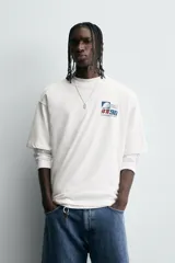 Camiseta blanca de corte relaxed fit, cuello redondo y manga corta. Estampado frontal con diseño gráfico en azul y rojo con texto en chino y la leyenda "Eastern Division 90".