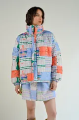 Campera puffer con estampado patchwork multicolor, cuello alto y bolsillos laterales.