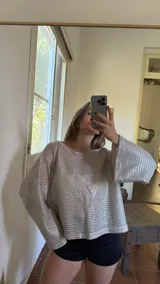 Blusa plateada de tejido metalizado con escote bote que puede usarse recto o caído en un hombro.