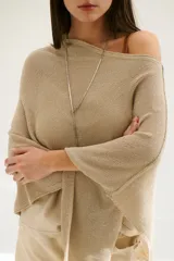Poncho color beige de tejido de punto con cuello asimétrico.