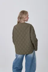 Campera acolchada negra, con diseño capitoné en rombos, cuello redondo y cierre frontal con botones a presión. Posee bolsillos delanteros amplios.