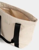 Bolso negro tipo shopper de tela deportiva con doble asa de hombro, cierre superior con tirador de cordón y goma, y etiqueta de goma con logo.