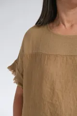 Remera color tostado de lino italiano, con escote a la base, corte amplio y mangas cortas con detalle de flecos.