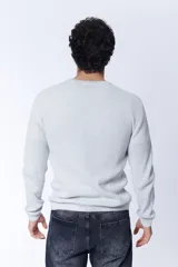 Buzo de tejido de punto con textura de gofre o waffle, color gris melange claro, de cuello redondo y manga larga.