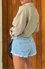 Short de jean de tiro bajo, color celeste claro lavado, con terminación deshilachada en el ruedo y roturas sutiles. Presenta costuras visibles en contraste y corte ajustado.