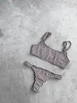 Conjunto de bikini con estampado geométrico en tonos celeste, azul, blanco, amarillo y naranja. El corpiño es bandeau con breteles regulables y lazo en la espalda. La bombacha es vedetina con frunce elástico en los costados.