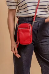 Bandolera compacta de símil cuero color rojo, con correa regulable y desmontable. Posee apertura superior, bolsillo frontal con cierre y bolsillo trasero abierto.
