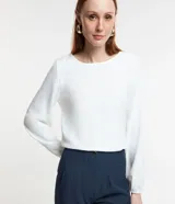 Blusa color lila confeccionada en crepé, con escote redondo y mangas largas con puños elásticos.