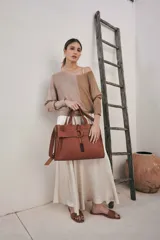 Bolso tote de cuero color marrón con correa larga ajustable y cierre con hebilla.