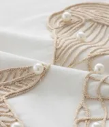 Remera de algodón blanco de corte regular, con cuello redondo y mangas cortas. Presenta un bordado frontal con motivos marinos como caracolas y una estrella de mar, acompañado de la frase "Bonjour La mer". Diseñada para la línea Curve & Plus Size.