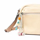 Bandolera color beige con correa de cuero marrón y charm colgante de cuentas de colores.