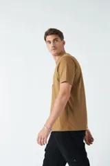 Remera color ocre de corte recto y manga corta, con cuello redondo y estampado rectangular con diseño floral en el frente.