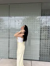 Pantalón de vestir amarillo con finas rayas verticales blancas, corte recto, tiro alto y bolsillos laterales.