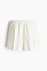 Short blanco de lino con cintura elastizada y cordón ajustable. Presenta pliegues frontales, bolsillos al bies y corte holgado.