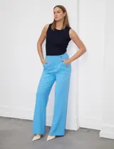 Pantalón largo de crepe elastizado color verde, de corte recto, con bolsillos delanteros y apliques de botones metálicos.